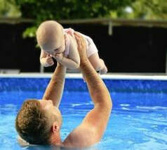 Picture of a man holding a small baby in a pool in North Little Rock Ar