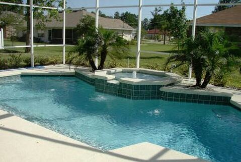 Nice Clean pool surrounded by a mosquito net fence, with a hot tub in the middle of the pool on the side deck